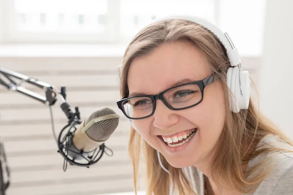 Radio host concept - Woman working as radio host sitting in front of microphone over white background in studio, close-up — Stock Photo, Image