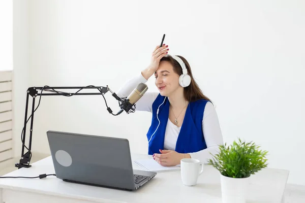 Radio host concept - Woman working as radio host sitting in front of microphone over white background in studio — Stock Photo, Image