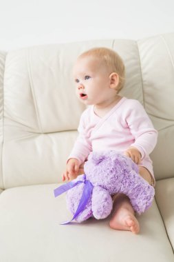 çocukluk, bebeklik ve insan kavramı - evde kanepede oturan mutlu küçük bebek kız
