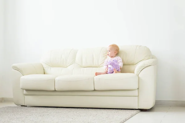 Infância, babyhood e conceito de pessoas - pequena menina feliz sentada no sofá em casa — Fotografia de Stock