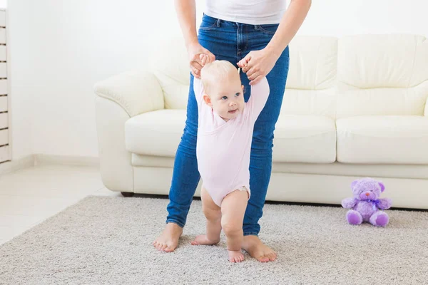 First steps of baby toddler learning to walk in white sunny living room. Footwear for child. — Stock Photo, Image