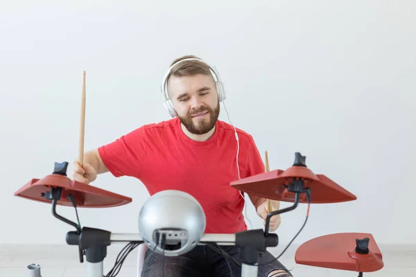 Emotions, electronic drums and people concept - young man drummer playing the drum