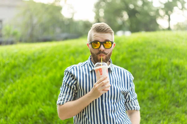 Knappe ontspannen jonge hipster man met een snor en baard luistert naar favoriete muziek op de koptelefoon tijdens het wandelen door het Park. Muziek abonnement concept en online radio. — Stockfoto
