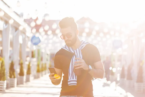 Knappe vrolijke jonge Arabische student met een stijlvolle snor en een baard met SAP in zijn handen, wandelen door de stad na een werkdag. Concept van positieve en rust. — Stockfoto