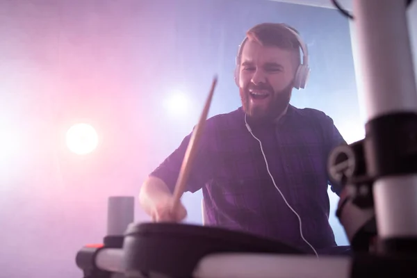 Mensen, muziek en hobby concept-emotionele man het spelen van elektronische drums op het podium — Stockfoto