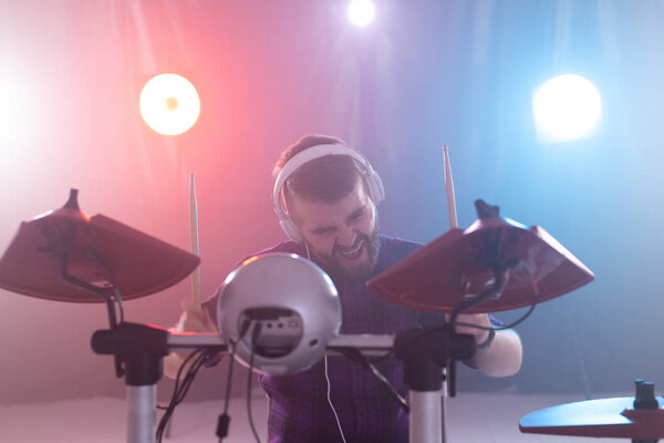 hobby, music and people concept - portrait of a man with white headphones playing drums, having fun