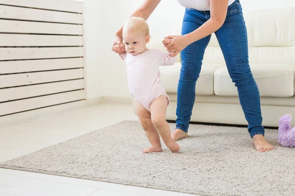아기 유아의 첫 번째 단계는 흰색 햇볕이 잘 드는 거실에서 걷는 법을 배워야합니다. 아동용 신발. — 스톡 사진