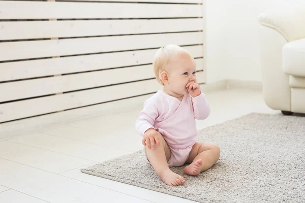 Liten krypande bebis flicka ett år gammal sitter på golvet i ljust ljus vardagsrum leende och skrattar. Happy småbarn Kid spelar hemma. Barndoms konceptet — Stockfoto