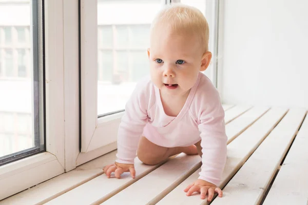 Childhood, family and infant concept - Little baby girl on windowsill at home — Stock Photo, Image