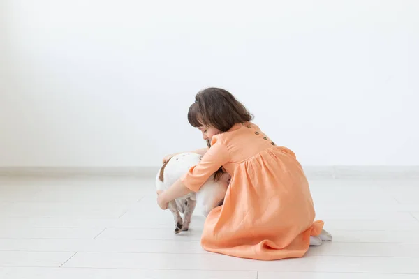 Concepto de propietario de niños y mascotas: niña pequeña sentada en el suelo con un lindo cachorro Jack Russell Terrier — Foto de Stock