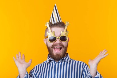 Sakallı çılgın genç pozitif hipster adam mutlu sarı bir arka plan üzerinde gülüyor. Tatil ve satış kavramı