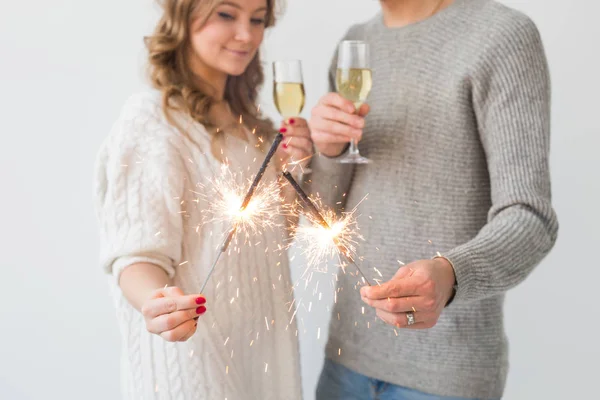 Ano Novo, feriados, data e dia dos namorados conceito - casal amoroso segurando faíscas luz e copos de champanhe sobre fundo branco close-up — Fotografia de Stock