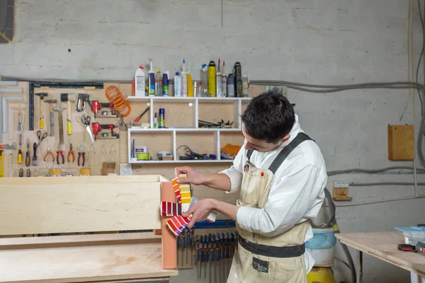 Молодий бородатий чоловік, що працює на меблевій фабриці, підбирає кольори для меблів — стокове фото