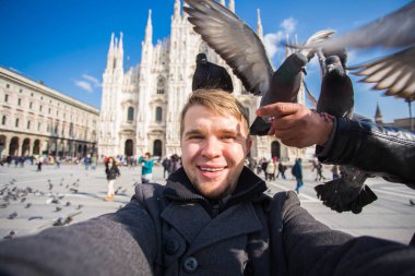 Kış seyahat, tatil ve kuşlar kavramı - yakışıklı erkek turist Milano'da ünlü Duomo Katedrali önünde selfie fotoğraf yapma komik güvercinler ile.