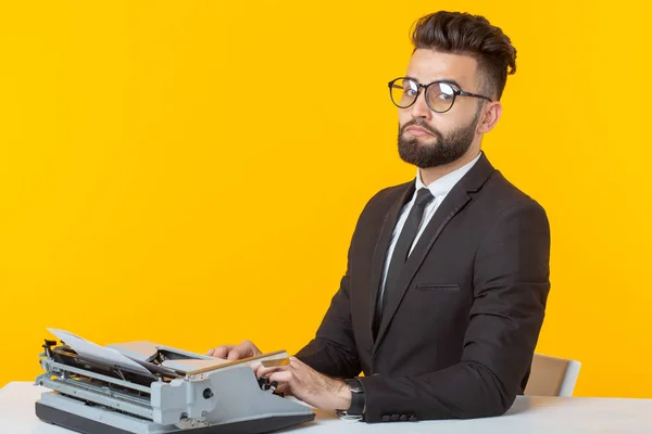Arabischer Geschäftsmann oder Manager im formellen Anzug tippt Text auf einer Schreibmaschine auf gelbem Hintergrund. Konzept der Geschäfts- und Büroarbeit — Stockfoto
