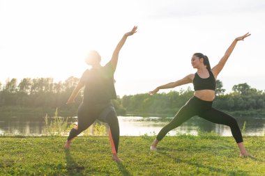Uyum ve sağlıklı yaşam tarzı konsepti - Spor giyim genç ince kadınlar yoga açık havada pratik.