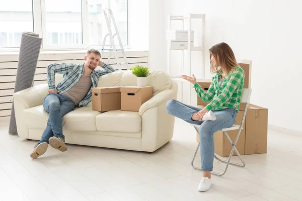 Casal alegre positivo se alegra em mover seu novo apartamento sentado na sala de estar com seus pertences. Conceito de aquecimento doméstico e hipotecas para uma família jovem . — Fotografia de Stock