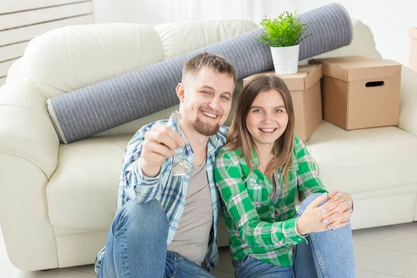 거실에 서있는 동안 새로운 아파트의 열쇠를 들고있는 젊은 긍정적 인 부부. 집안일 및 가족 모기지 개념. — 스톡 사진