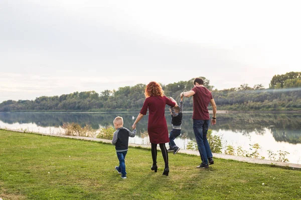 Eltern, Kindheit und Naturkonzept - Familie spielt mit zwei Söhnen am Wasser — Stockfoto