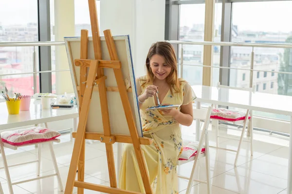 Sanat sınıfı, çizim ve yaratıcılık konsepti - Palet ve fırça ile şövale önünde oturan kız öğrenci — Stok fotoğraf