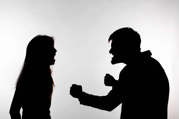 Concept d'agression et de maltraitance - homme et femme exprimant la violence domestique dans une silhouette de studio isolée sur fond blanc . — Photo