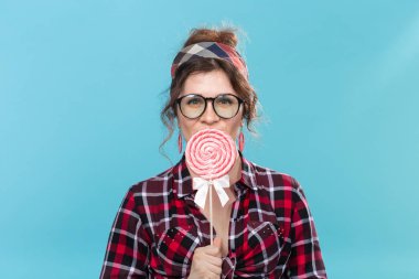 şeker, diyet ve abur cubur kavramı - mavi arka plan üzerinde büyük lolipop ile pin-up kadın portresi