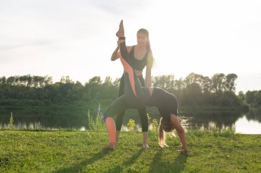 Uyum ve sağlıklı yaşam tarzı konsepti - Spor giyim genç ince kadınlar yoga açık havada pratik.