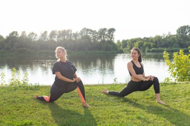 Uyum ve sağlıklı yaşam tarzı konsepti - Spor giyim genç ince kadınlar yoga açık havada pratik.