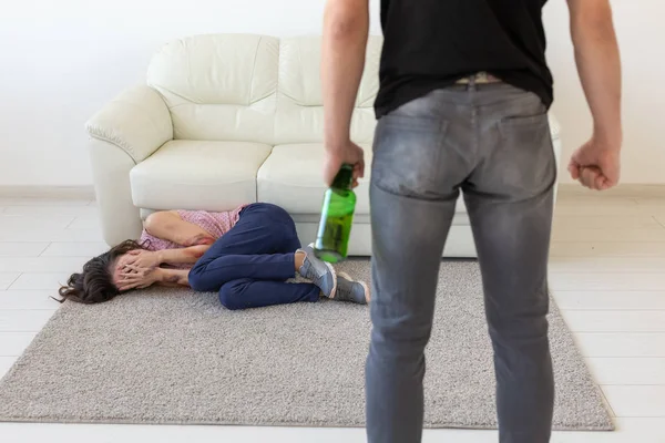 Ofiara, przemocy, nadużyć i alkoholowe koncepcja - pijany człowiek z butelki w pobliżu jego żona na podłodze — Zdjęcie stockowe