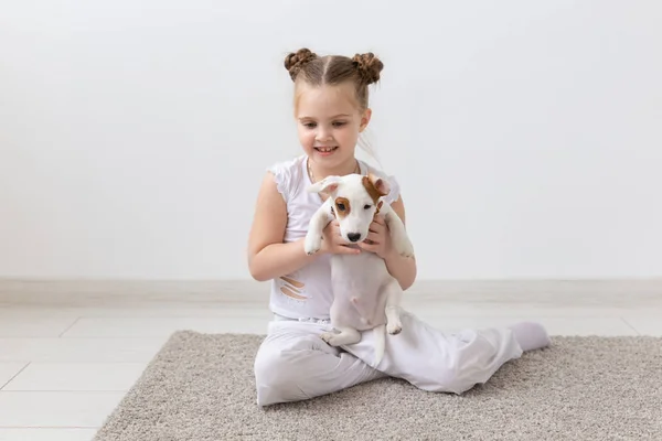 people, children and pets concept - little kid girl lying on the floor with cute puppy Jack Russell Terrier