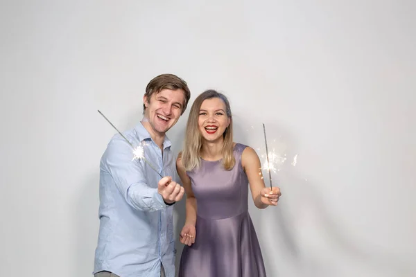 Festa, diversão, ano novo, Natal e feriados conceito - jovem casal feliz com brilhos no fundo branco — Fotografia de Stock