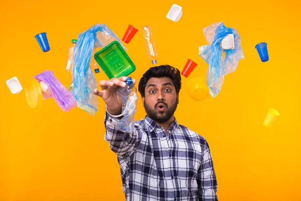 Környezetvédelmi világnap, műanyag újrahasznosítás probléma és a környezeti katasztrófa koncepció-meglepett indiai férfi gazdaság gyűrött műanyag palackot a sárga háttér. Ő aggódik ökológia — Stock Fotó