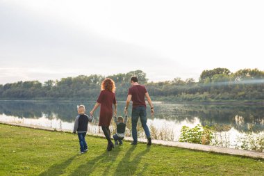 Ebeveynlik ve doğa kavramı -Güneşli bir günde bir nehir tarafından yaz bir parkta iki erkek ikiz çocuk ile anne ve baba ailesi