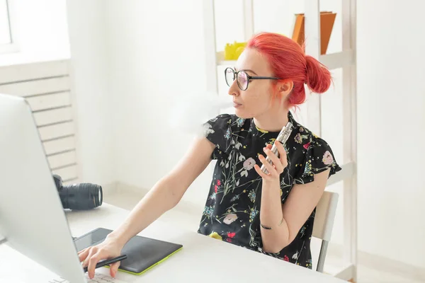 Konzept der Grafikdesignerin - Grafikdesignerin arbeitet am Computer, während sie am Schreibtisch im Büro ein Grafik-Tablet benutzt und einen Dampf raucht — Stockfoto