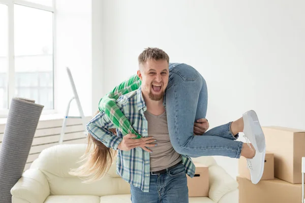 Giovane coppia pazza in pantaloni di jeans divertirsi gioire nel loro nuovo appartamento durante il trasferimento. Il concetto di housewarming e di credito per le nuove abitazioni . — Foto Stock