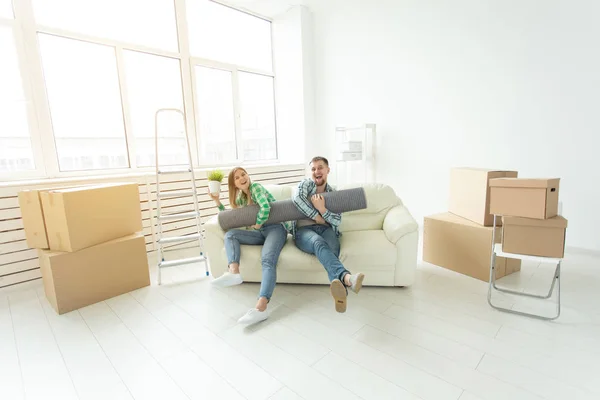 Jovem alegre alegre casal encantador menina e homem bonito segurando uma caixa com coisas e um pote com uma planta enquanto se muda para um novo apartamento. Conceito de habitação e hipoteca . — Fotografia de Stock