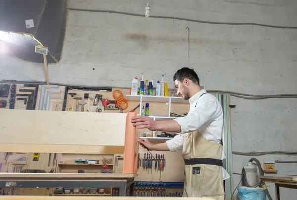 Маленькие компаньоны, мебель и концепция рабочего - Молодой человек, работающий на мебельной фабрике — стоковое фото