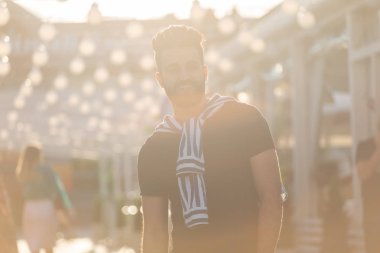 Bir bıyık ve sakallı sevimli şık Arap genç erkek hipster ve bir sokakta yürüyen gözlük giyiyor. Yaz tatili konsepti.