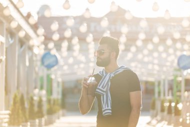 Şık bir bıyık ve elinde meyve suyu ile bir sakal ile yakışıklı neşeli genç arap öğrenci, bir iş gününden sonra şehir etrafında yürüyüş. Pozitif ve dinlenme kavramı.