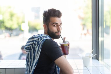 Pozitif genç şık adam iş yerinde bir mola sırasında bir kafede suyu içme. Dinlenme ve sağlıklı atıştırmalık kavramı.