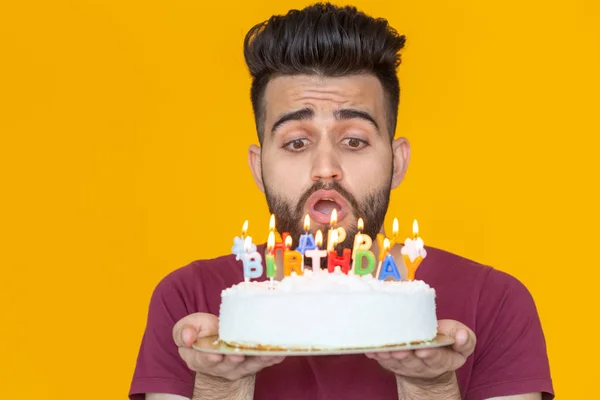 Young male hipster with a beard holding a cake with the inscription happy birthday congratulations on the anniversary and the holiday. Concept of promotions and discounts.