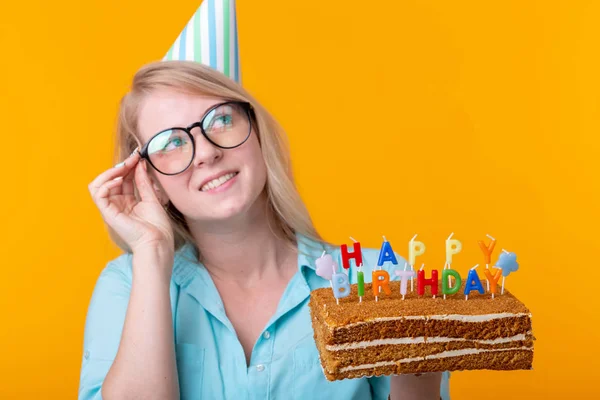 휴일 및 파티 cocept - 노란색 배경에 포즈를 취하는 생일 케이크를 들고 긍정적 인 젊은 여성. — 스톡 사진