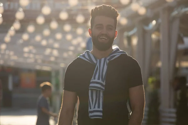 Guapo joven estudiante árabe alegre con un bigote elegante y una barba caminando por la ciudad después de un día de trabajo. Concepto de positivo y descanso . — Foto de Stock