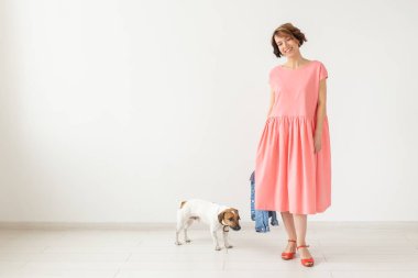 evcil hayvan sahibi kavramı - beyaz arka plan üzerinde jack russell terrier köpek ile pembe elbise genç kadın