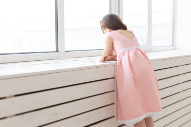 Pembe elbiseli rüya gibi küçük kız pencereden dışarı bakıyor