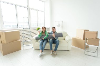 Neşeli neşeli genç çift büyüleyici kız ve yeni bir daireye hareket ederken bir bitki ile şeyler ve bir pot ile bir kutu tutan yakışıklı adam. Ev ve mortgage konsepti.