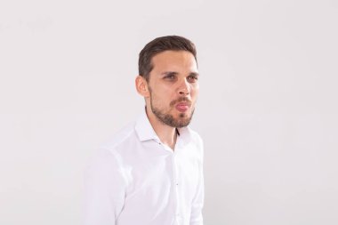 Sakallı ve bıyıklı yakışıklı komik adam beyaz arka planda dilini gösteriyor. Duygu ve duygular.