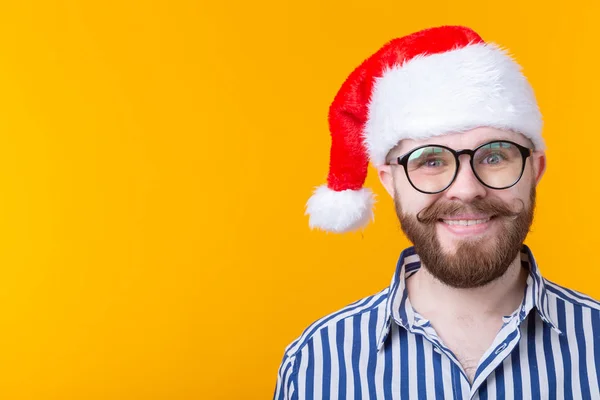 लाल सांता क्लॉस टोपी में सुखद पागल प्यारा युवा हिपस्टर पुरुष पीले पृष्ठभूमि पर खड़ा है। क्रिसमस और नए साल की अवधारणा। विज्ञापन स्थान . — स्टॉक फ़ोटो, इमेज