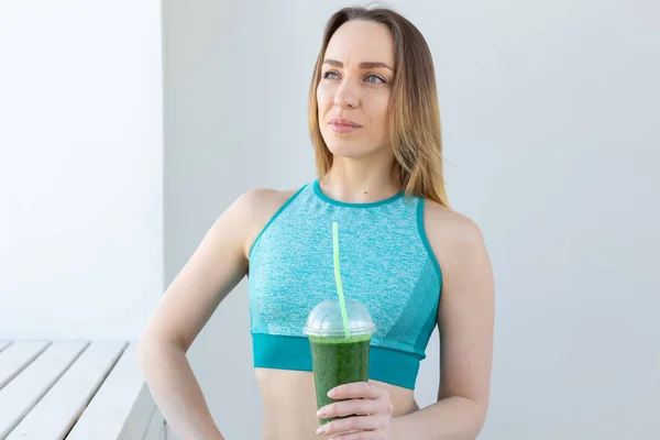 Concetto sano, fitness e disintossicazione - primo piano della giovane donna in abbigliamento sportivo con frullato verde all'interno — Foto Stock