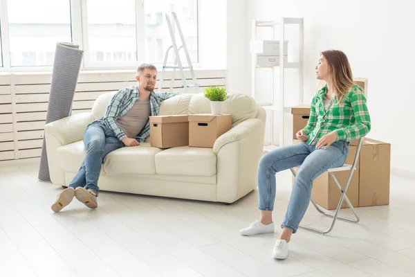 Casal alegre positivo se alegra em mover seu novo apartamento sentado na sala de estar com seus pertences. Conceito de aquecimento doméstico e hipotecas para uma família jovem . — Fotografia de Stock